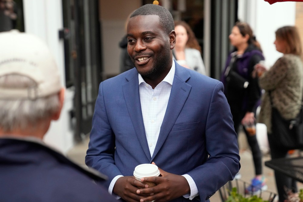 Gabe Amo talks to people outside of a cafe