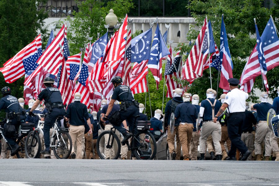 Carrying shields, covering their faces, and holding upside down U.S. flags, marchers with the Alt-Right Neo-Nazi group 
