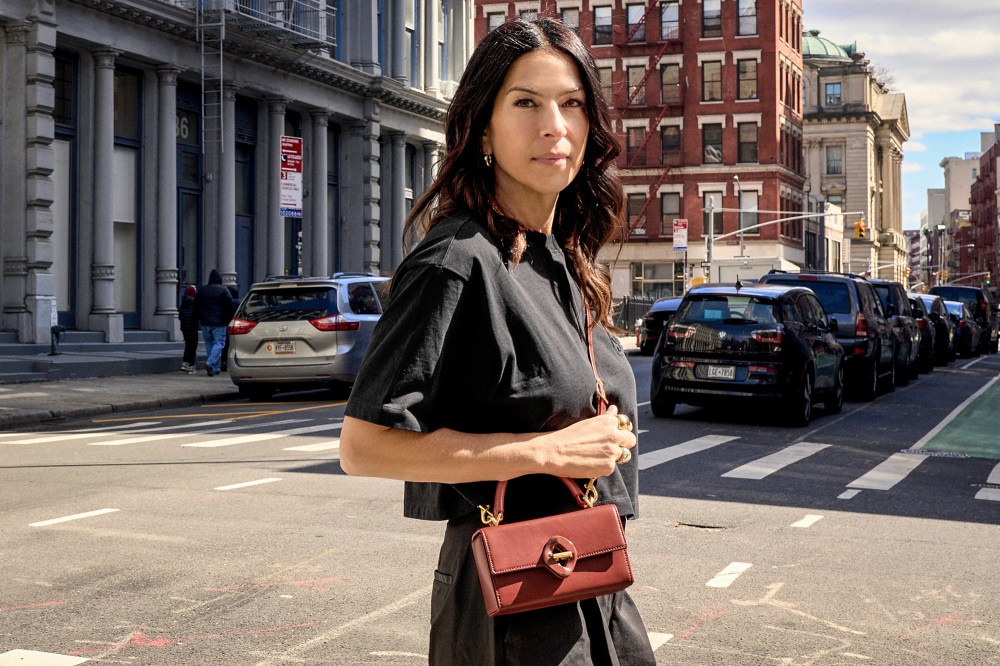Rebecca Minkoff stands on the crosswalk of a street in the city on a sunny day