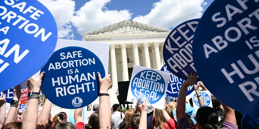 People hold signs saying "Safe Abortion is a Human Right" and "Keep abortion legal"