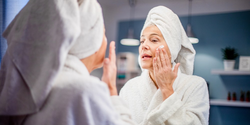Mature woman applying face cream.