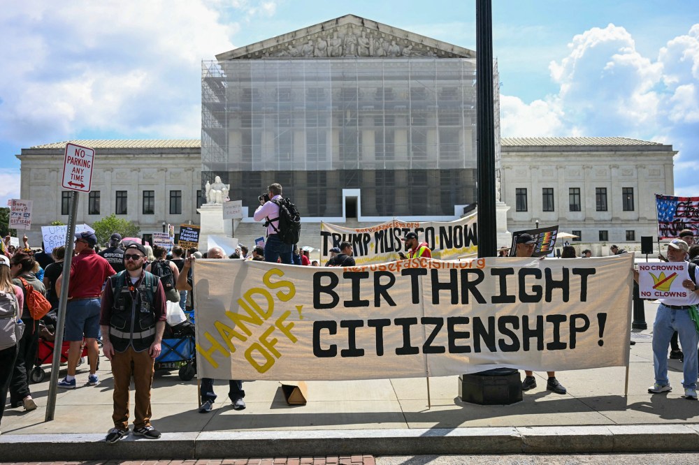 Image: People hold banners and signs as they participate in a protest outside the Supreme Court