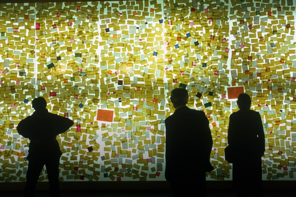 Curious visitors read sticky notes on a wall. (Photo by Construction Photography/Corbis)