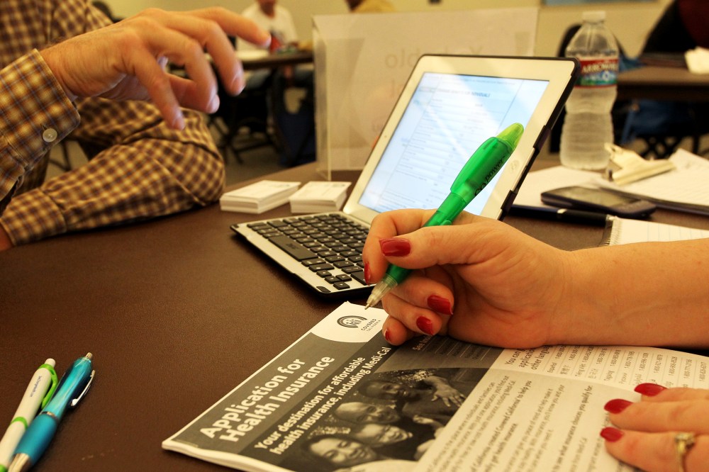 A healthcare reform specialist helps people select insurance plans at an ACA Enrollment Fair in Pasadena, Calif. Nov. 19, 2013.