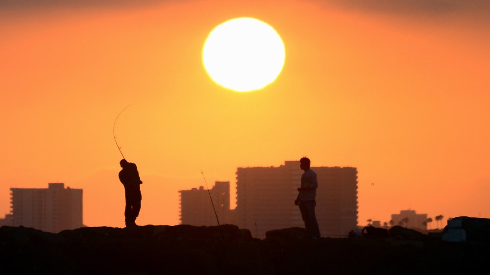 A fisherman casts his line from the rocks at Seal Beach, Calif., as the sun prepares to set on June 28, 2014. (Photo by Frederic J. Brown/AFP/Getty)