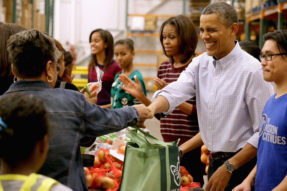 President Barack Obama, first lady Michelle Obama, and their daughters Sasha Obama, 12, and Malia Obama, 15, help pack and distribute bags of food to needy children and seniors at the Capital Area Food Bank November 27, 2013 in Washington, DC.