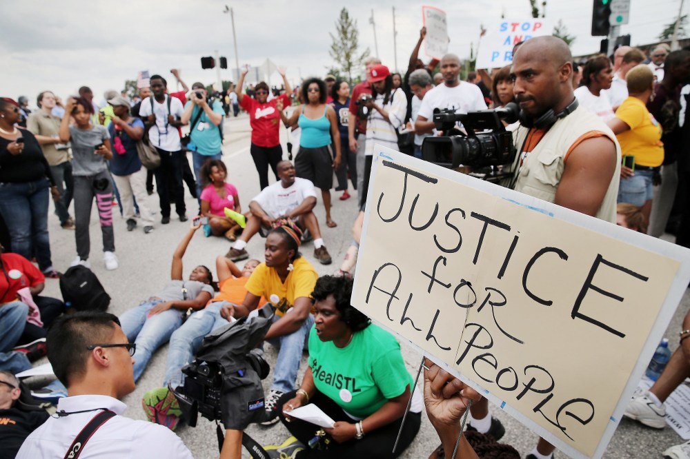 Demonstrators sit in the street after police prevented them from gaining access to Interstate Highway 70 during a protest on Sept. 10, 2014 near Ferguson, Mo.
