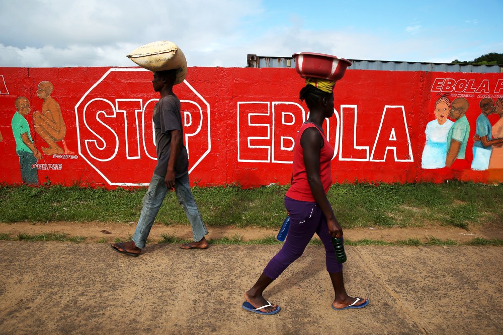People pass an Ebola awareness mural on October 2, 2014 in Monrovia, Liberia.