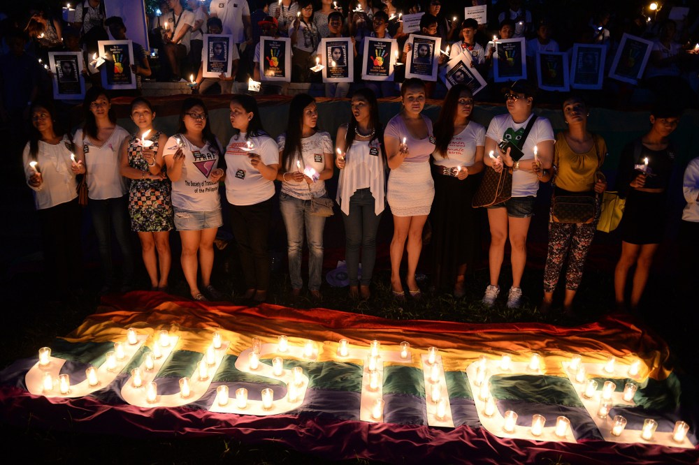 Protesters hold candles during a vigil inside the campus of the state university in Manila on Oct. 24, 2014, to coincide with the burial of murdered transgender woman, Jennifer Laude. (Photo by Ted Aljibe/AFP/Getty)