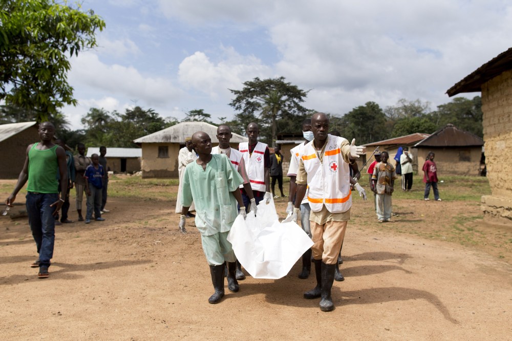 Health workers from Guinea's Red Cross carry the body of a victim of the Ebola virus in Momo Kanedou in Guinea on Nov. 19, 2014. (Photo by Kenzo Tribouillard/AFP/Getty)