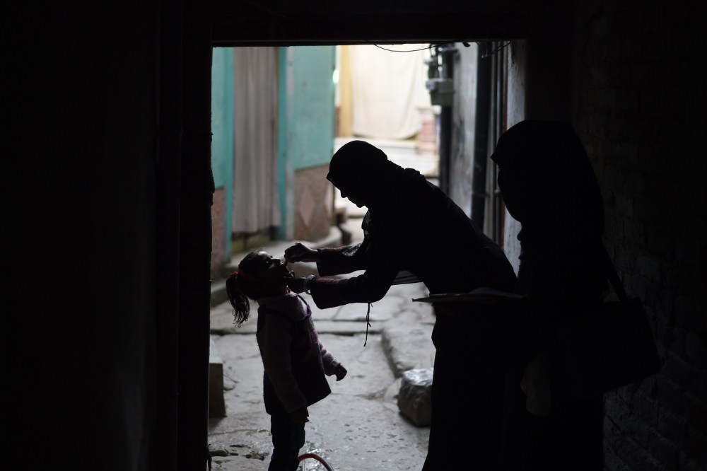 A Pakistani health worker (R) administers the polio vaccine to a child during a vaccination campaign in Rawalpindi on Dec. 9, 2014. (Photo by Farooq Naeem/AFP/Getty)