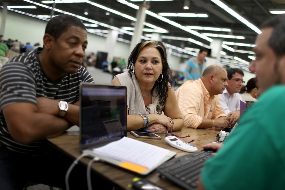 Jose Ramirez and Mariana Silva speak with Yosmay Valdivia, an agent from Sunshine Life and Health Advisors, as they discuss plans available from the Affordable Care Act on Dec. 15, 2014 in Miami, Fla. (Joe Raedle/Getty)