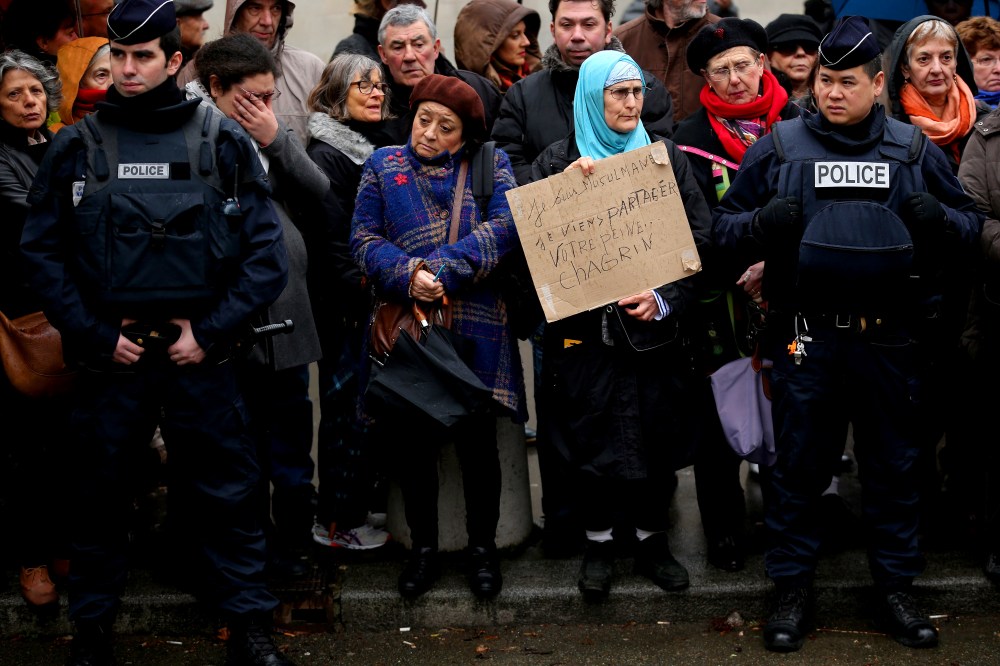 Amid tight security, a woman holds up a sign saying 'I am a Muslim. I come to share your grief' as members of the public pay respects at the funeral of Charlie Hebdo a cartoonist on Jan. 15, 2015 in Paris, France. (Photo by Christopher Furlong/Getty)
