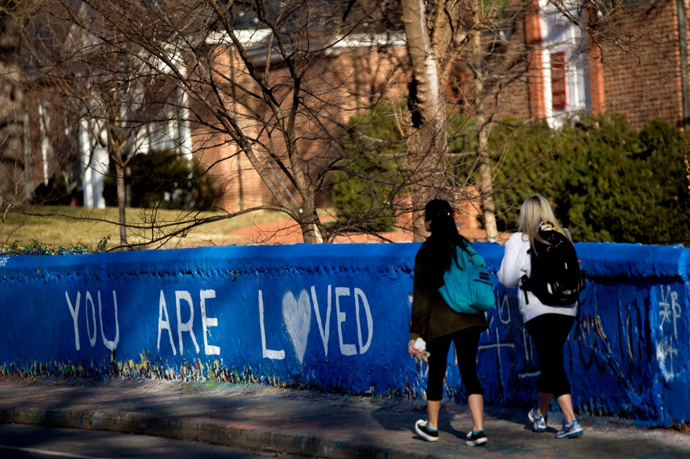 Students walk past the message "You are Loved" painted on a wall next to the Beta Bridge near the University of Virginia campus in Charlottesville, Va. on Jan. 16, 2015.