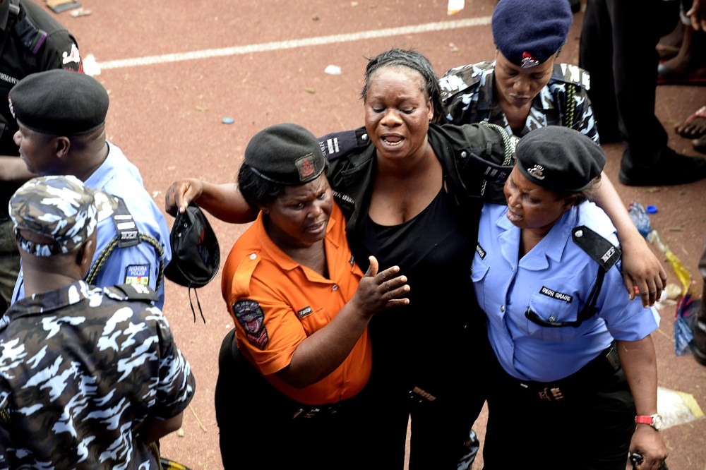 Policewomen help a colleague injured during fracas that broke out during a presidential campaign rally of Nigeria's main opposition All Progressives Congress (APC) at Taslim Balogun Stadium in Lagos on Jan. 30, 2015. (Photo by Pius Utomi Ekpei/AFP/Getty)