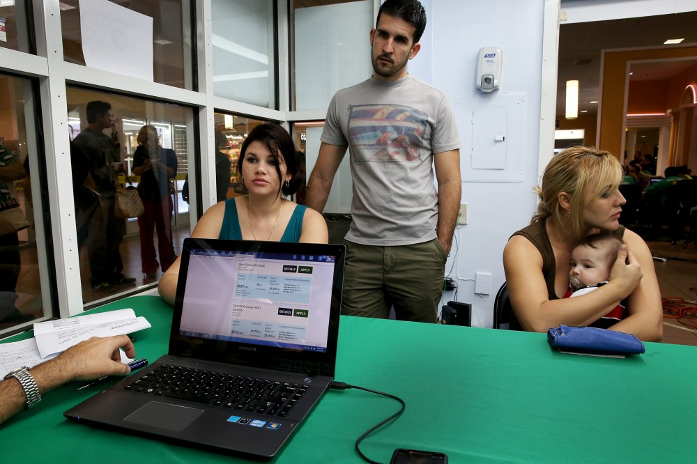 Dailem Delombard, Ronnie Cabrera and Maylin Lezcano sit with an insurance agent from Sunshine Life and Health Advisors in Miami, Jan. 5, 2014.