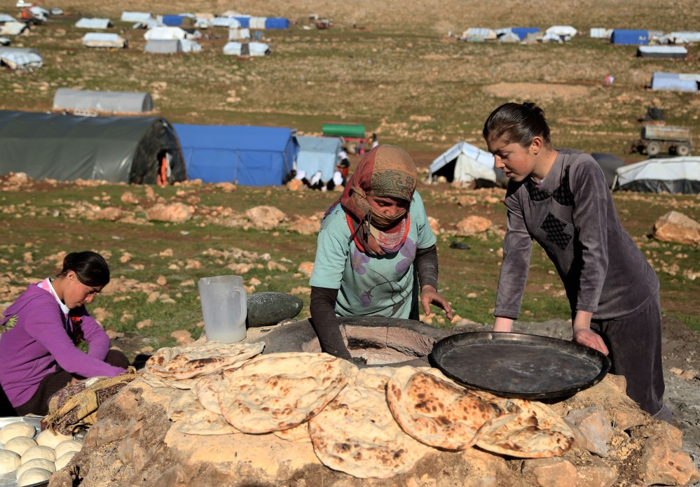 Yezidi women bake bread on the outskirts of Sinjar mountain, Mosul, March 2, 2015, after fleeing from ISIS attacks to a shelter in the Sinjar Mountain. (Photo by Emrah Yorulmaz/Anadolu Agency/Getty)