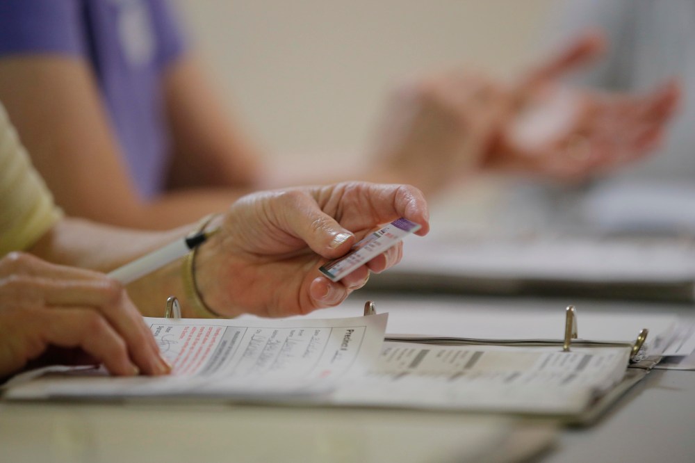 An election worker checks a voter's drivers license as North Carolina's controversial "Voter ID" law goes into effect for the state's presidential primary election at a polling place, March 15, 2016, in Charlotte, N.C. (Photo by Chris Keane/Reuters)