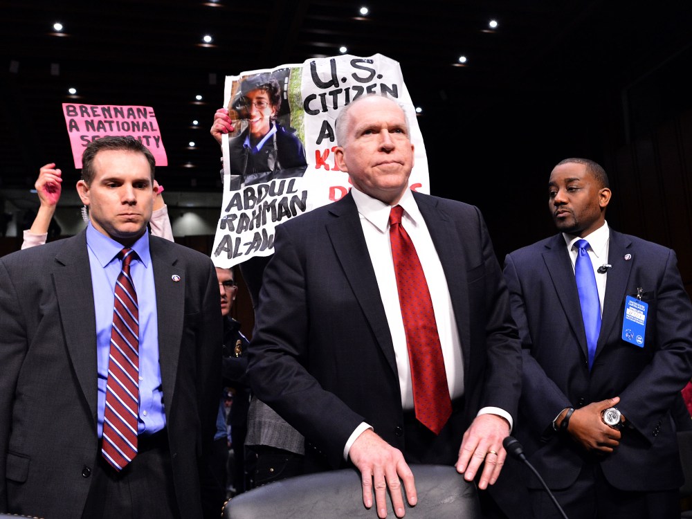 Anti-war protesters (back) shout slogans as John Brennan (C), US President Barack Obama's pick to lead the CIA, arrives to testify before a full committee hearing on his nomination to be director of the Central Intelligence Agency  (CIA) in the Hart...