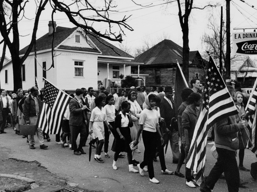 Circa 1965:  Participants, some carrying American flags, marching in the civil rights march from Selma to Montgomery, Alabama in 1965  (Photo by Buyenlarge/Getty Images, File)