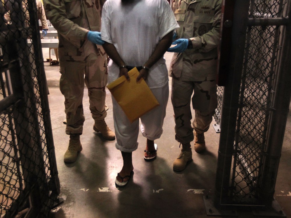 File Photo:  U.S. Navy guards escort a detainee after a "life skills" class at Camp 6 in the Guantanamo Bay detention center on March 30, 2010 (Photo by John Moore/Getty Images, File)