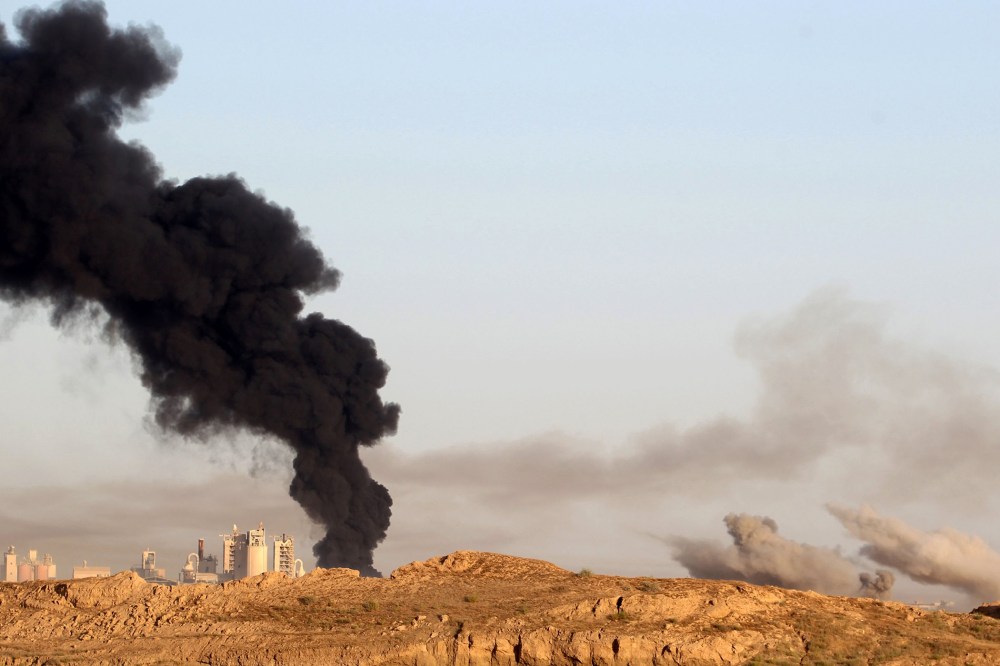 Smoke billows in the background as Iraqi pro-government forces advance towards the city of Fallujah on May 23, 2016, as part of a major assault to retake the city from Islamic State (IS) group. (Photo by Ahmad Al-Rubaye/AFP/Getty)