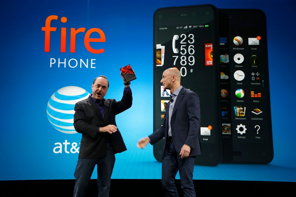 Ralph de la Vega, left, President and CEO of AT&T Mobility, accepts a gift from Amazon CEO Jeff Bezos, right, of what Bezos said is the first Amazon Fire Phone off the assembly line at the launch event for the new smartphone, Wednesday, June 18, 2014, in
