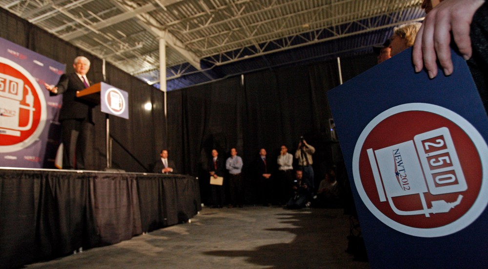 A supporter holds a campaign sign of Republican presidential candidate, former House Speaker Newt Gingrich, left, promoting his goal of $2.50 a gallon gas as he speaks at a rally in Brandon, Miss., Sunday, March 11, 2012.