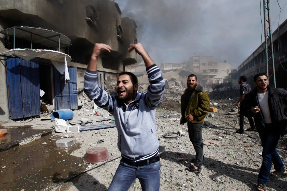 Palestinians call for help as they stand next to a damaged building after an Israeli air strike in Gaza City on Sunday. (AP Photo/Adel Hana)