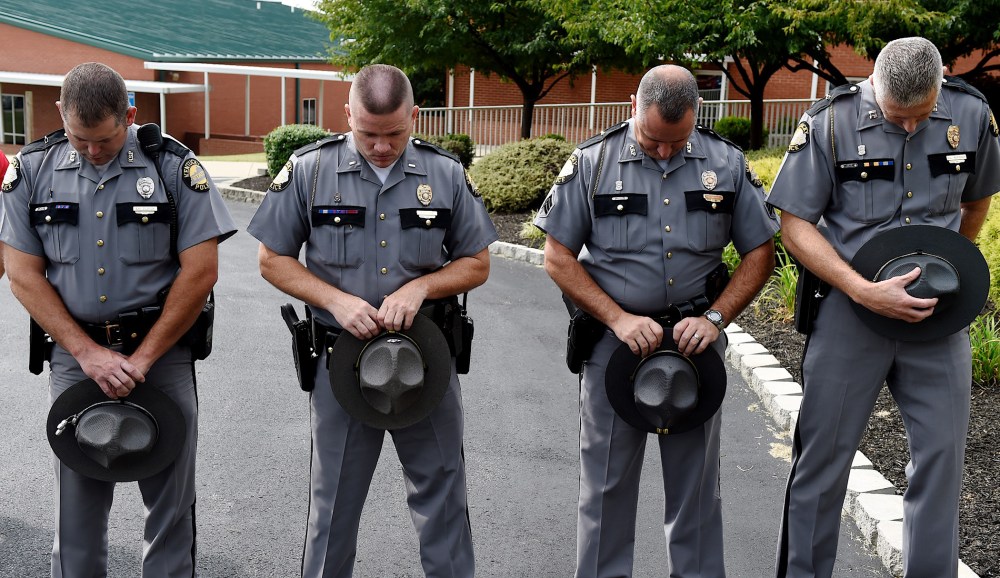Kentucky State Troopers, from left, Eric Dilback, Lonnie Bell, Chris McKee, and Sean McKinney bow in prayer during a road renaming ceremony in memory of Chase Trent in Zion, Ky., Aug. 29, 2015. (Photo by Darrin Phegley/The Gleane/AP)