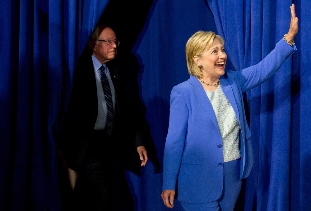 Democratic presidential candidate Hillary Clinton, followed by Sen. Bernie Sanders, I-Vt., waves as they arrive for a rally in Portsmouth, N.H., July 12, 2016, where Sanders endorsed Clinton for president. (Photo by Andrew Harnik/AP)