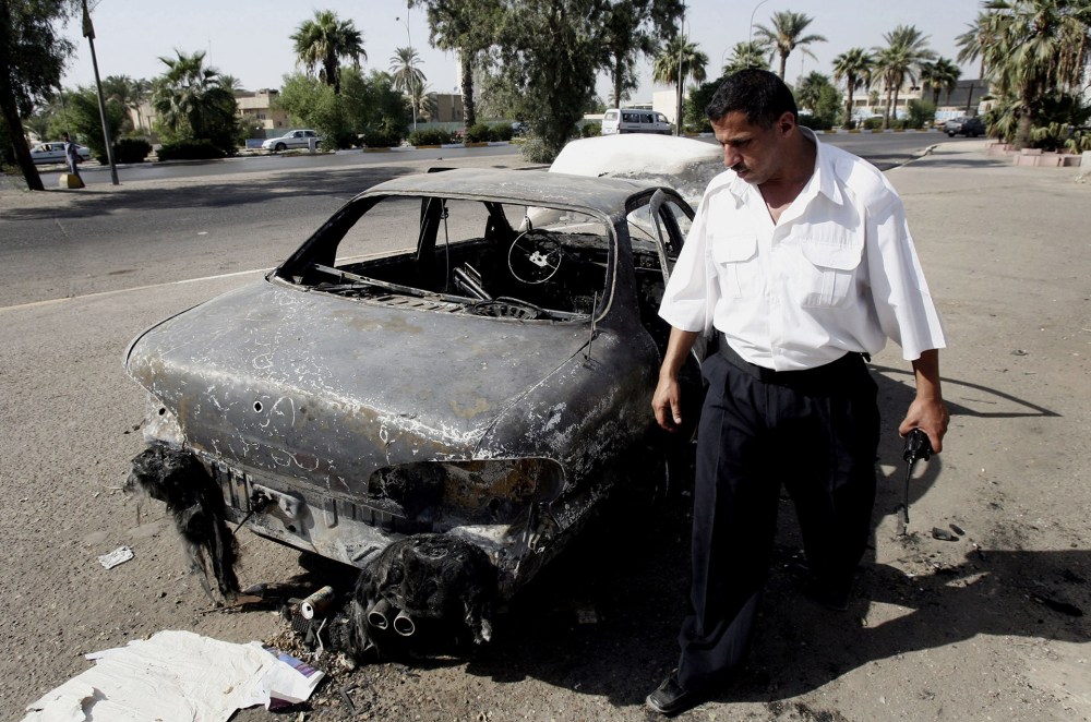 In this Sept. 25, 2007 file photo, an Iraqi traffic policeman inspects a car destroyed by a Blackwater security detail in al-Nisoor Square in Baghdad, Iraq. (Khalid Mohammed/AP)