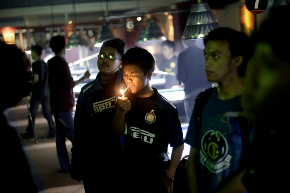 A soccer fan lights up a cigarette while watching a match at a cafe in Jakarta, Indonesia, on Oct. 27, 2013.