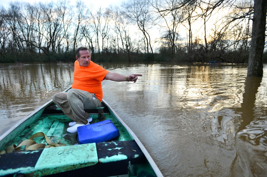 Wayne Horton points out some of his crops, now under water, as he steers his boat over his flooded orchard next to his house on Clinton Street in Courtland, Ala., Dec. 26, 2015. (Photo by Jeronimo Nisa/The Decatur Daily/AP)