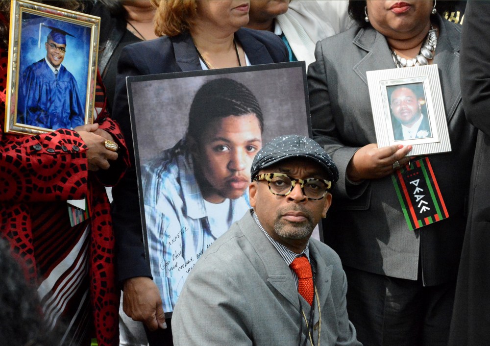 Filmmaker Spike Lee appears at a news conference, May 14, 2015 in Chicago, flanked by parents holding photographs of the children they've lost to gun violence in Chicago. (Photo by Brian Jackson/Sun-Times Media/AP)