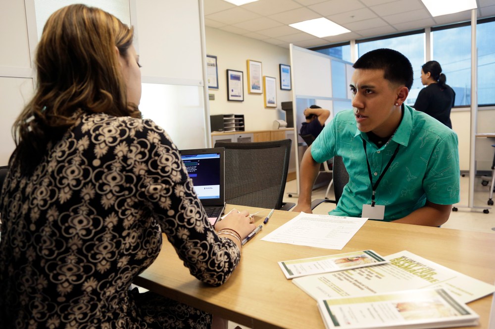 Navigator Dianelys Dominguez, left, assists Giovanny Vega, 18, of Miami, right, sign up for health insurance under the Affordable Care Act, Nov. 17, 2014, in Miami, Fla. (Photo by Lynne Sladky/AP)