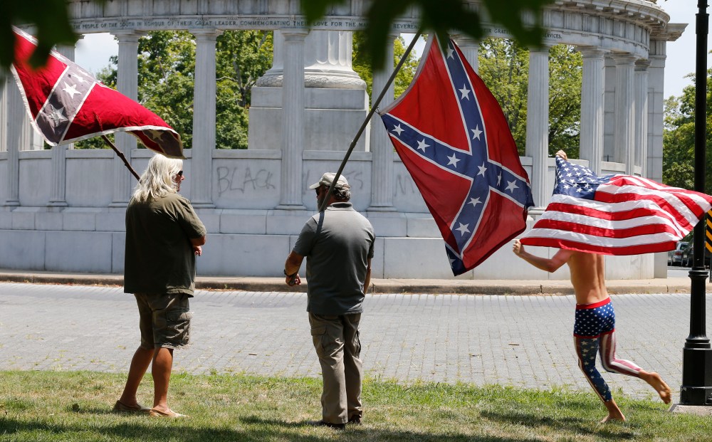 Members of the Virginia Flaggers demonstrate near the monument for Confederacy President Jefferson Davis as a runner carries an American flag, June 25, 2015, on Monument Avenue in Richmond, Va. (Photo by Steve Helber/AP)