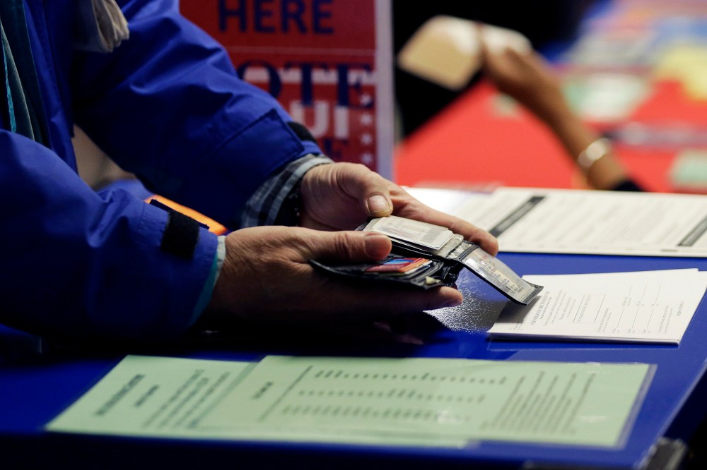 A voter shows his photo identification to an election official at an early voting polling site, in Austin, Texas on Feb. 26, 2014.