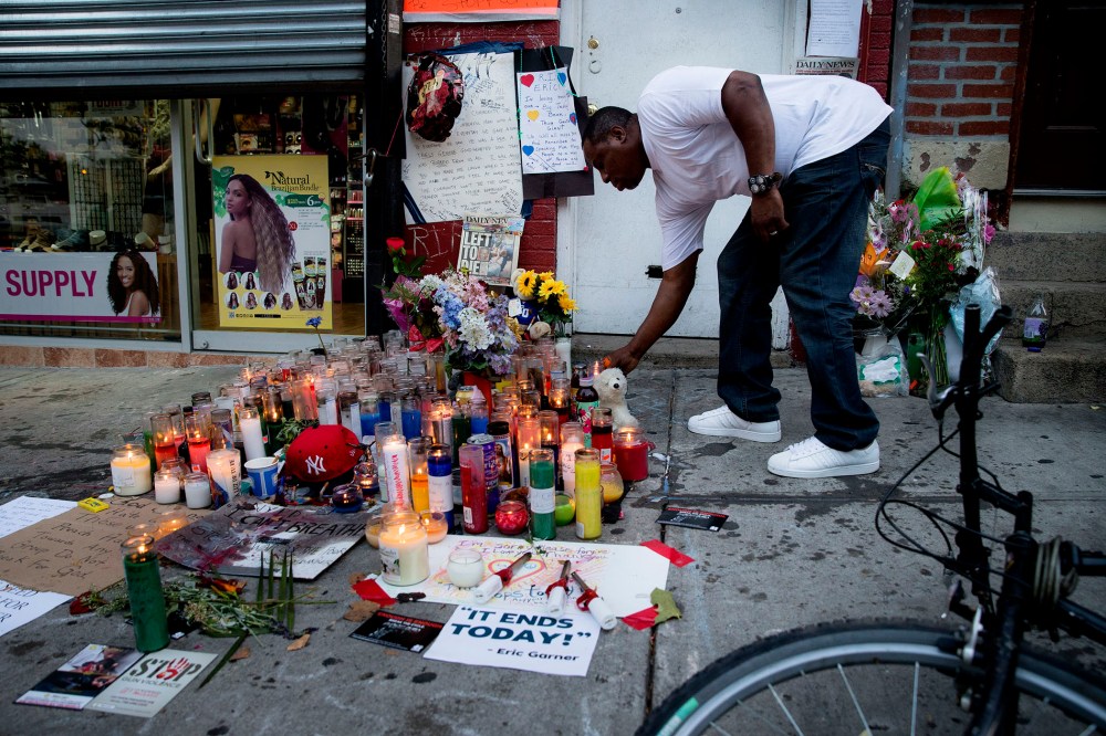 A mourner places a candle at a memorial for Eric Garner, a Staten Island man who died while being arrested by New York City police, on July 22, 2014, in New York. (Photo by John Minchillo/AP)