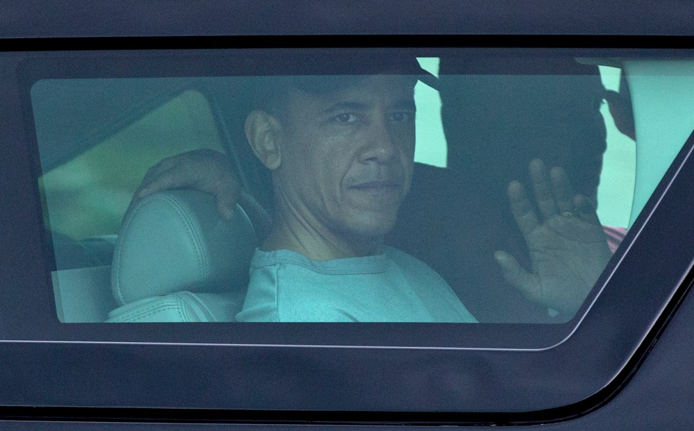President Barack Obama waves from the window of his motorcade vehicle as he returns from a workout at Marine Corp Base Hawai. The president and the first family are in Hawaii for a family holiday vacation. (Photo by Carolyn Kaster/AP)