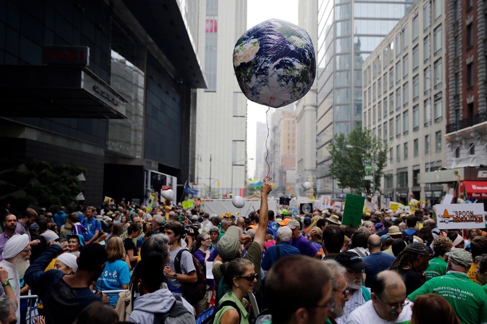 A man throws an earth balloon into the air as people fill 58th Street between 8th and 9th Avenue before a global warming march in New York Sunday, Sept. 21, 2014. (Photo by Mel Evans/AP)