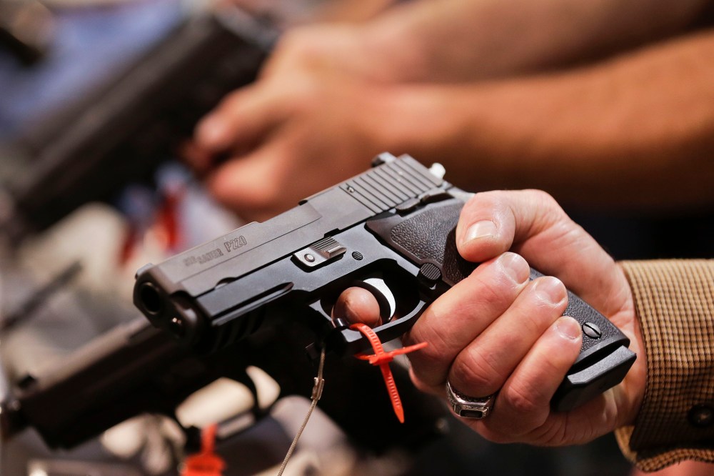 A convention attendee handles a .45 caliber semiautomatic pistol at a trade show on Jan. 15, 2013, in Las Vegas, Nev. (Photo by Julie Jacobson/AP)