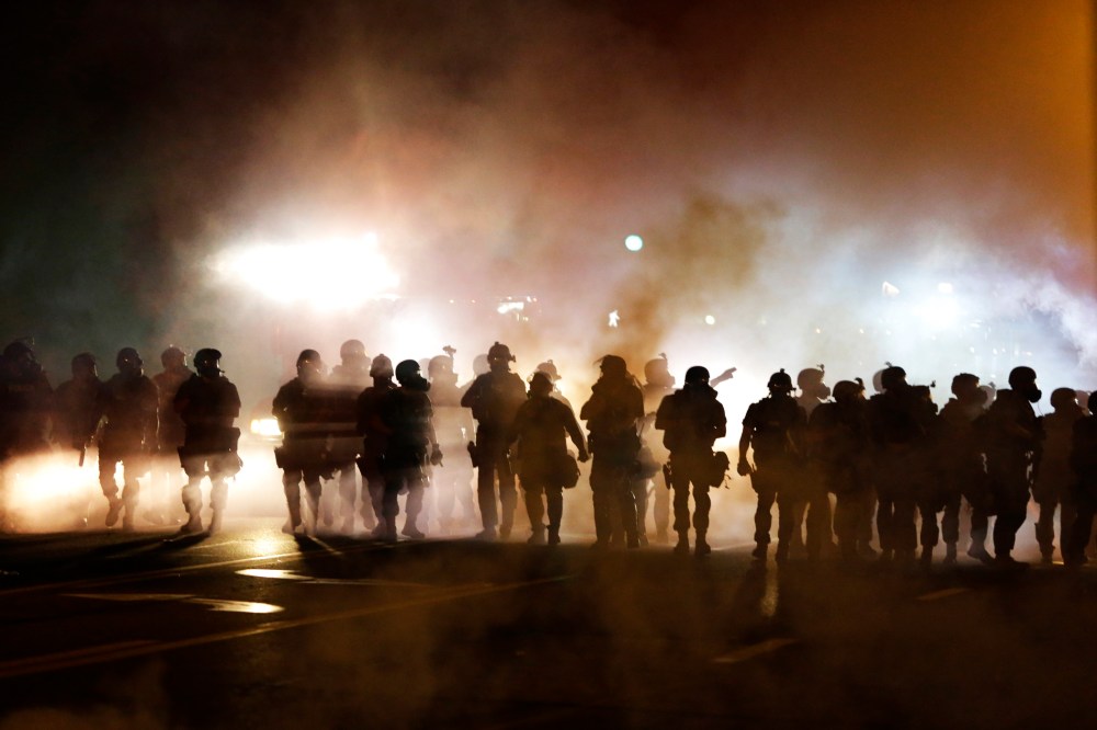 Police advance through smoke, Wednesday, Aug. 13, 2014, in Ferguson, Mo.
