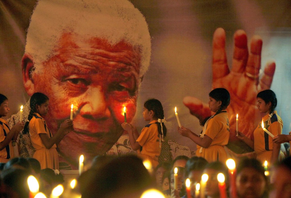 Schoolchildren hold candles near a giant portrait of former South African President Nelson Mandela in Chennai, India, Dec. 6, 2013.