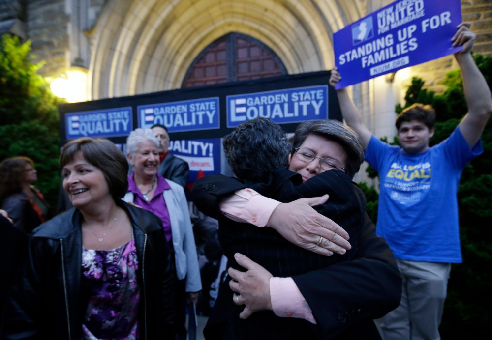Cindy Meneghin, second from right, hugs her attorney Hayley Gorenberg during a rally at Garden State Equality in Montclair, N.J., after a Superior Court Judge ruled that New Jersey is unconstitutionally denying federal benefits to gay couples and must all