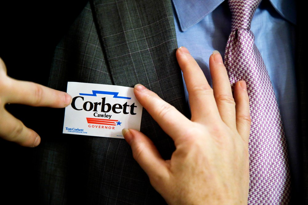 A supporter of Pennsylvania Gov. Tom Corbett places a campaign sticker, Nov. 7, 2013.