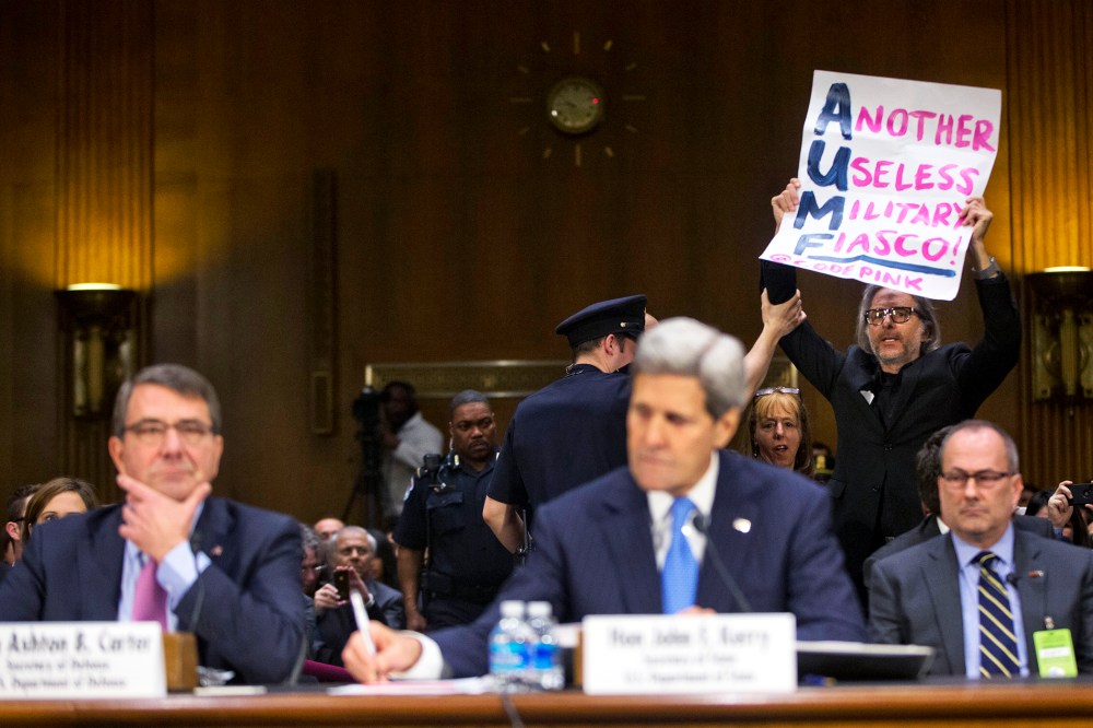 A CodePink demonstrator is escorted out by a member of the Capitol Police on Capitol Hill in Washington, D.C., March 11, 2015. (Photo by Pablo Martinez Monsivais/AP)