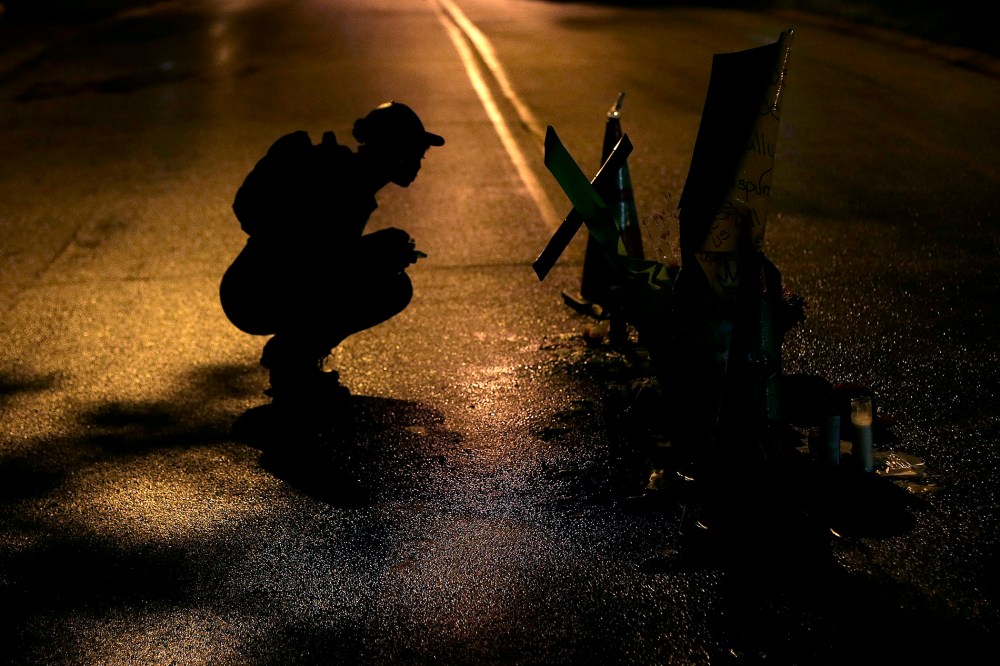 A woman pauses, Aug. 15, 2014, before a makeshift memorial in the middle of the street where Michael Brown was killed by police Aug. 9 in Ferguson, Mo.