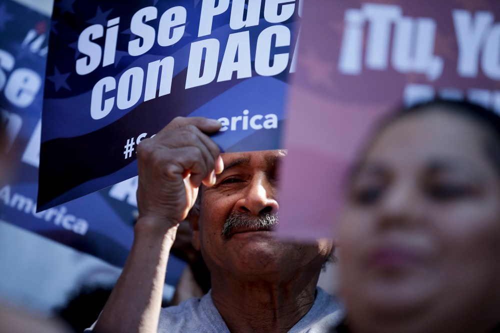 A man stands among signs during a rally in support of President Barack Obama's plan to protect more than 4 million people living illegally in the U.S. from deportation on Feb. 17, 2015, in San Diego. (Photo by Gregory Bull/AP)