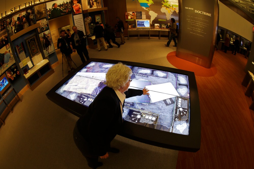 Docent Patricia Flynn demonstrates an interactive with information about conflicts in Afghanistan and Iraq during a tour of the George W. Bush Presidential Center Wednesday, April 24, 2013, in Dallas. More than 8,000 people are expected to attend the...